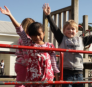 2 children on the playground with arms in the air. 
