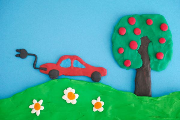 Concept image of electric car, apple tree and hill, made from play clay (Plasticine).