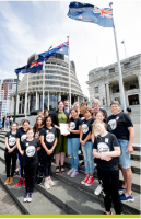 A group of girls with some adults stand on the steps of NZ parliament.
