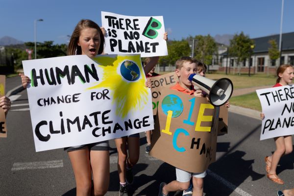 Students holding banners protesting about climate change. Main banners read " Human change for climate change' and " There is no Planet B." One student is speaking into a loud hailer.