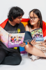 Two people sitting wrapped in a rainbow flag reading resource booklets.