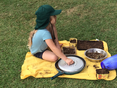 Student making mud pies outside.