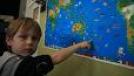 Student pointing to New Zealand on a world map.