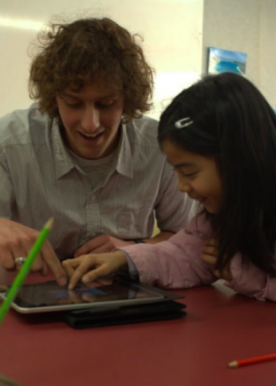 Student using an iPad with teacher